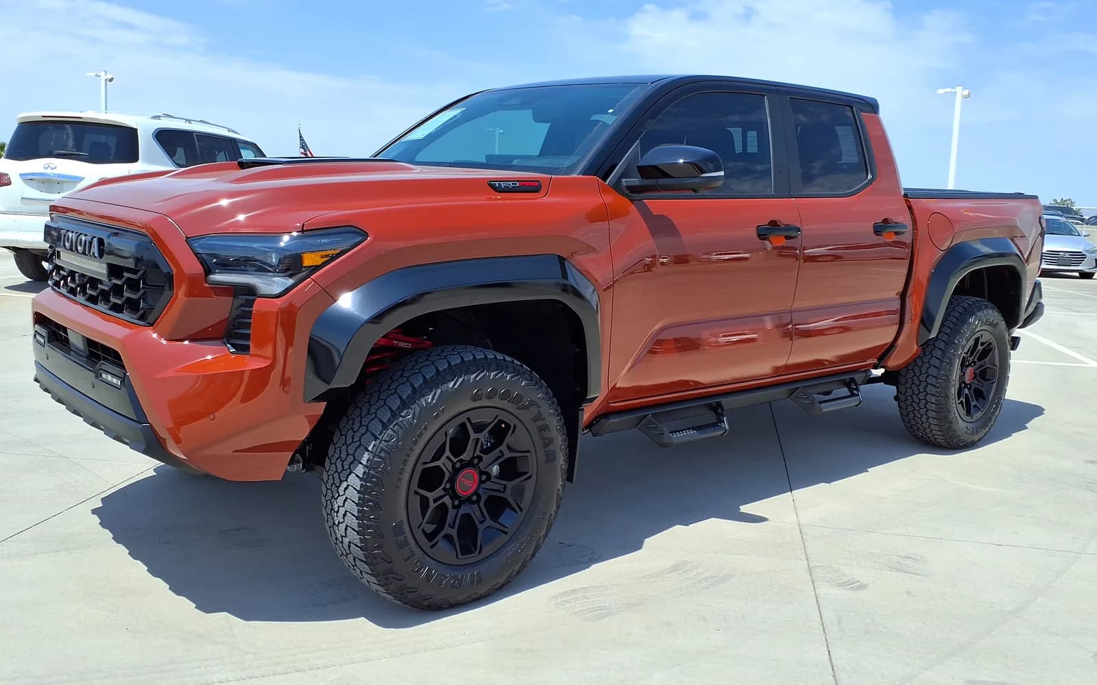 Toyota Tacoma TRD Pro color Terra (naranja), cuarta generación N400 de doble cabina, en tres cuartos frontal izquierdo en el patio de un concesionario. Se distinguen la parrilla heritage con TOYOTA en letras de bloque, la toma de aire del capó con emblema TRD, los rines negros con tapa central roja y los resortes rojos de la suspensión. Imagen referencial del modelo, no de la unidad en venta.